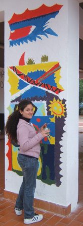 Immagine con una alunna che lavora su un murales posto su un muro esterno della scuola