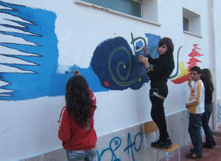 Immagine con alunni che lavorano su un murales posto su un muro esterno della scuola